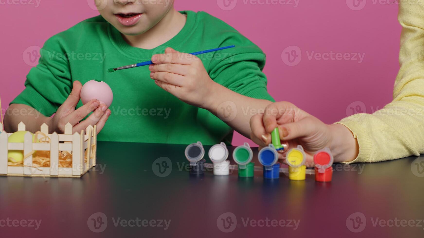 Young adorable kids coloring easter eggs with watercolor paint, creating lovely designs to celebrate spring holiday. Cheerful brother and sister painting festive decorations in studio. Camera A. photo