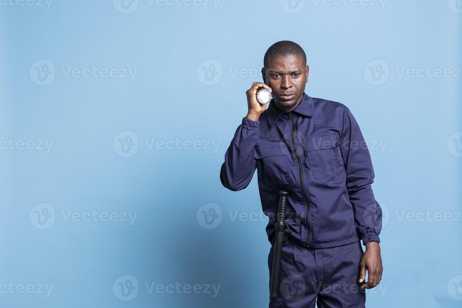 African american security guard patrolling the premises at night, using his flashlight to inspect the perimeter in the dark. Male agent examining the area with a lantern for safety. photo