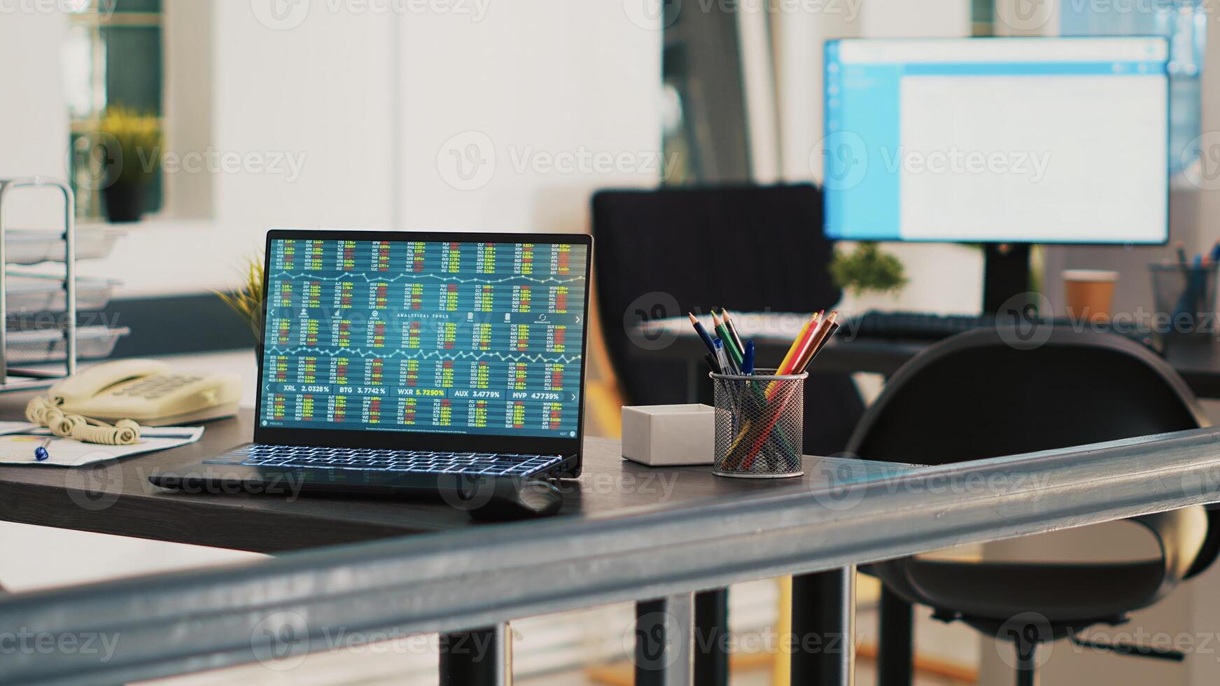 Office with laptop showing stock market listings and display in background with scheduled clients list. Notebook with trading platform indexes and customers financial consultations list in the back photo