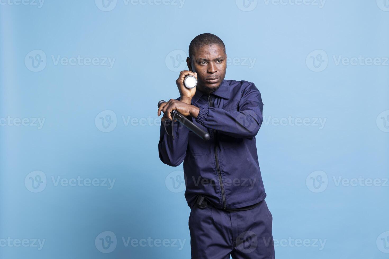 Security guard patrolling the premises with a flashlight and baton, working on protecting and safeguarding the perimeter in the dark. Skilled armed agent inspecting the area, ensure safety. photo