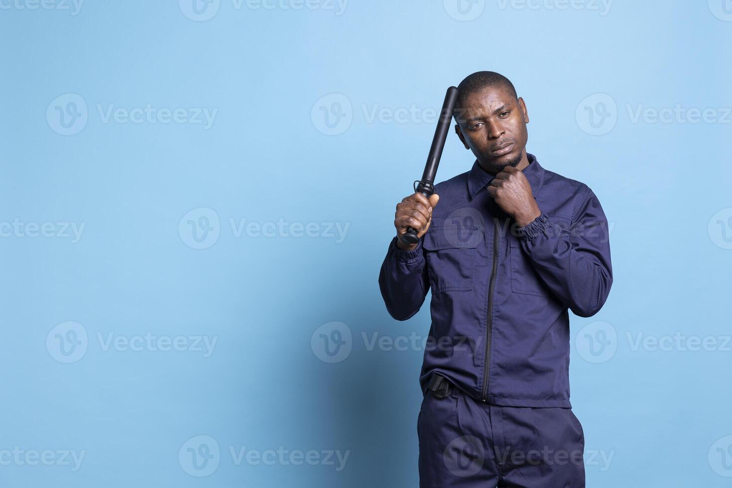 Security officer poses with a police baton and his fist clenched, making threats in case of attack or emergency fights. Guard on protection duty trained to punch and use his uniform weapon. photo