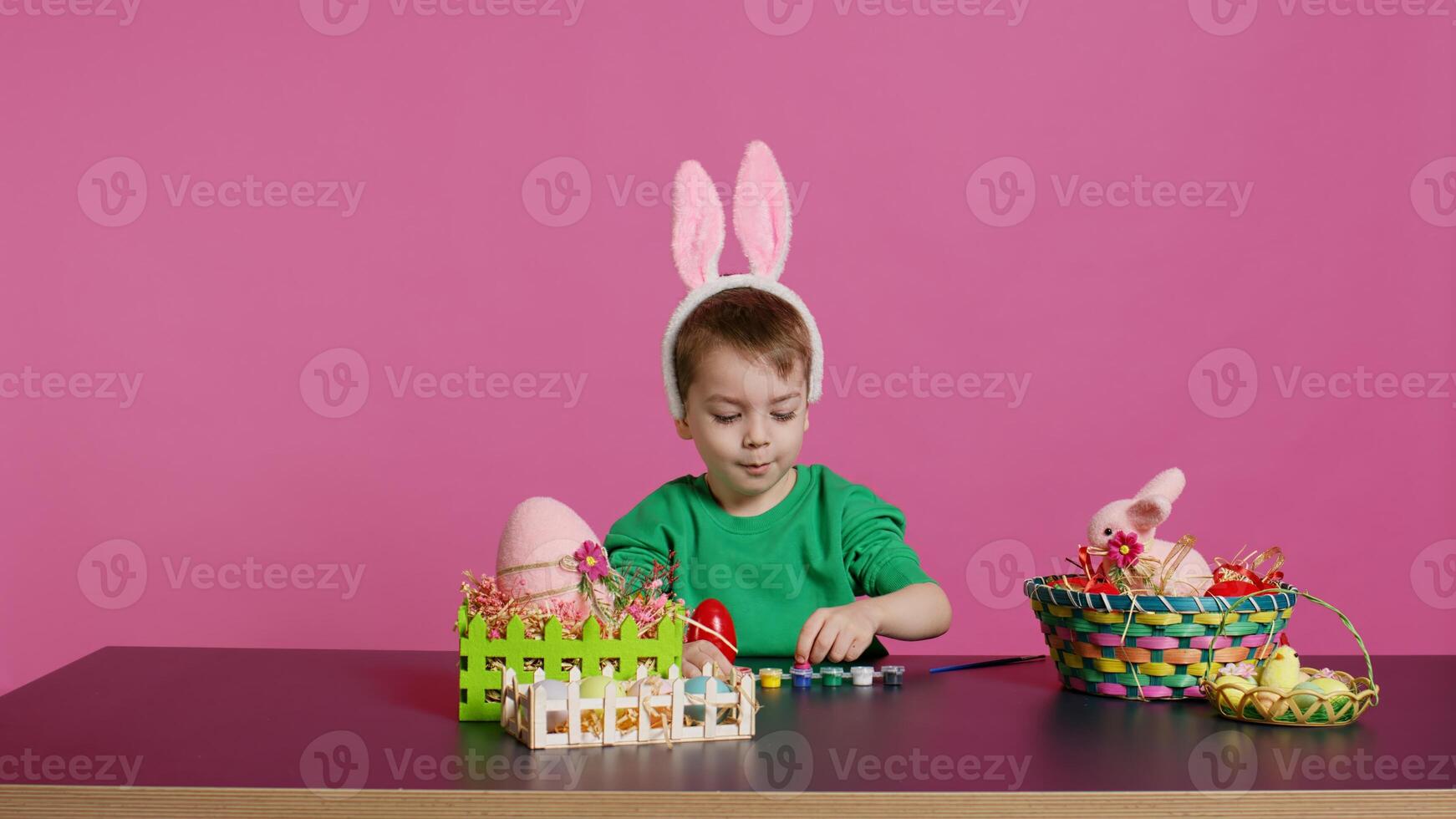 Adorable little youngster creates handcrafted ornaments for Easter Sunday and painting eggs with stamps and brushes. Pleased young boy using art materials to color and decorate. Camera B. photo