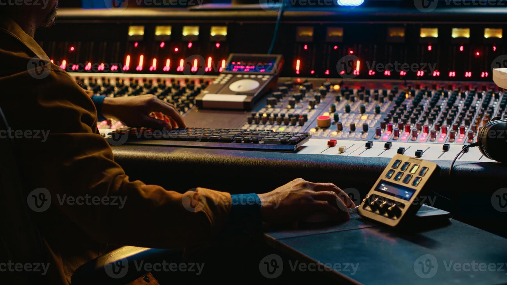 African american sound designer working with editing software to produce new tracks. Audio engineer uses mixer and compressor, changes volume level and sound settings in post production. Camera A. photo