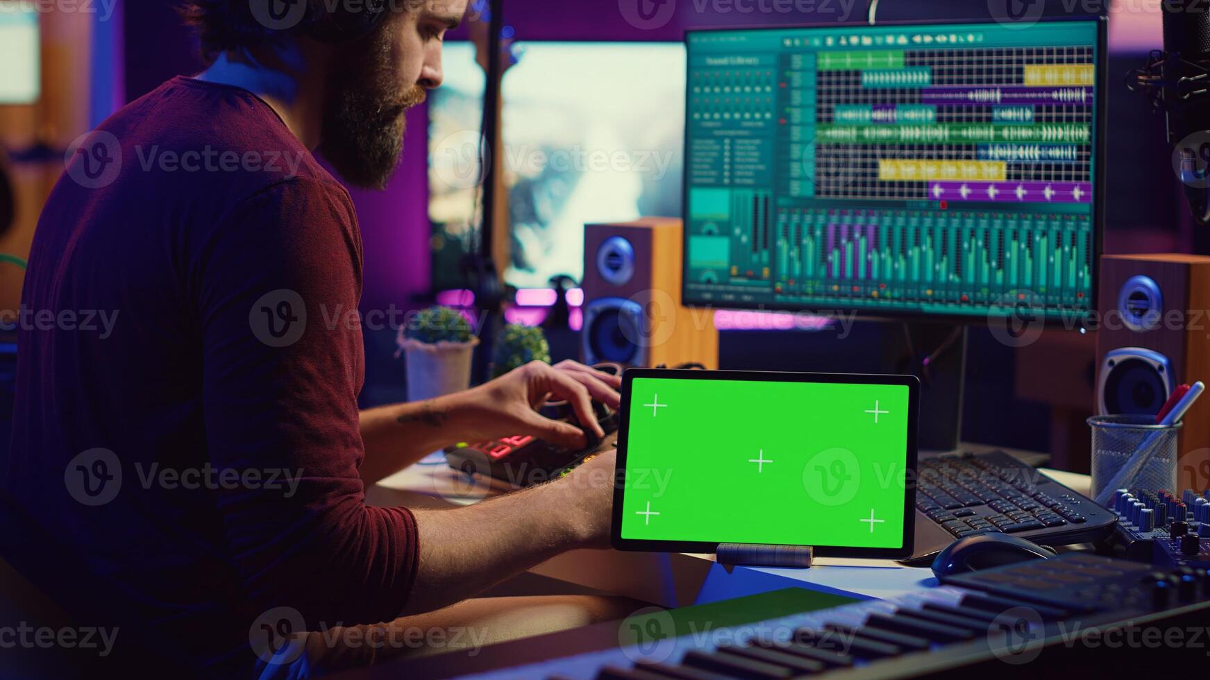 Musician mixing and mastering sounds at home studio with electronic console and soundboard, creating modern tunes. Sound engineer producing audio tracks with greenscreen on tablet. Camera A. photo