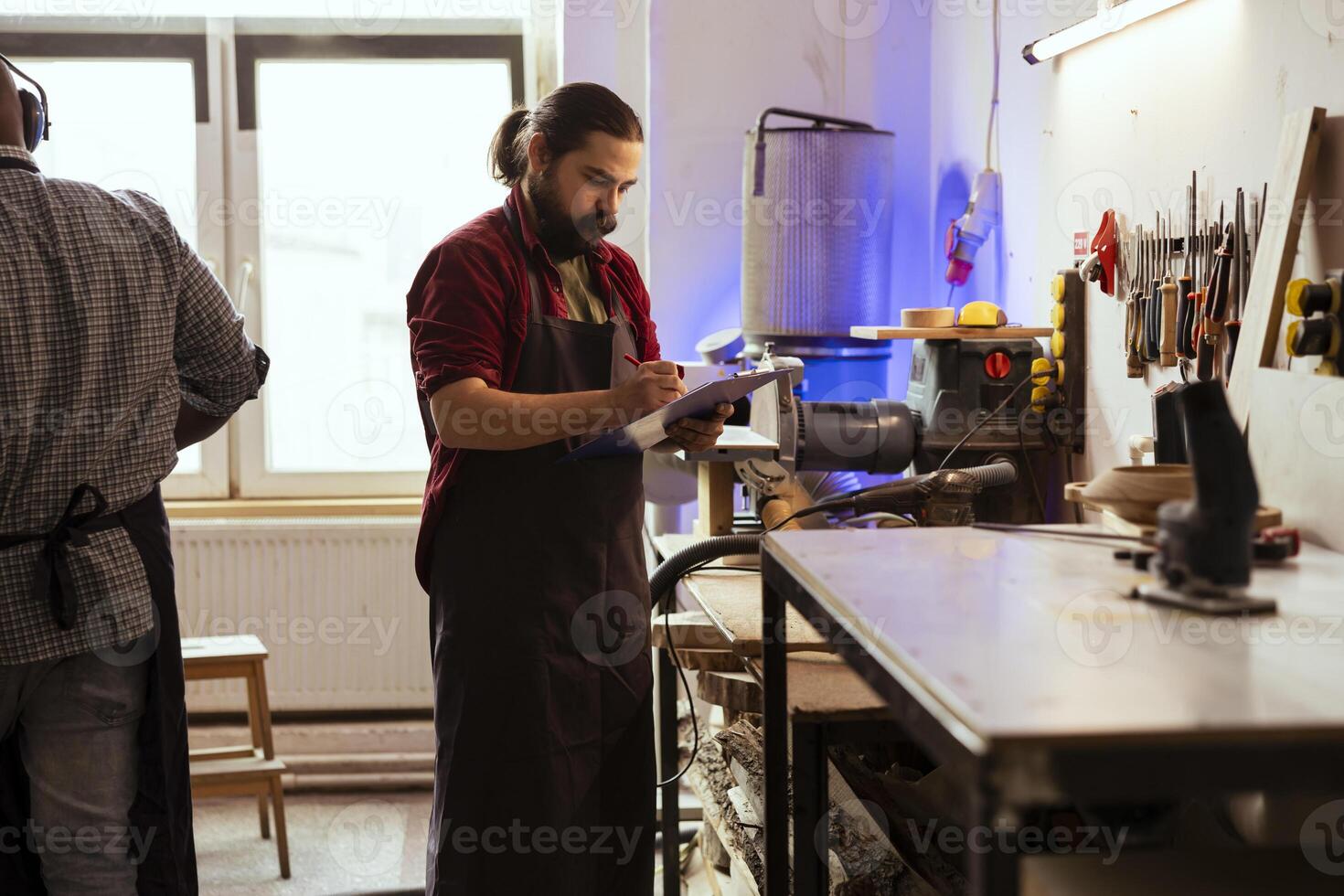 Carpenter drawing blueprints on notepad in studio, transforming creative ideas into tangible wood art pieces. Artisan looking at technical schematics to execute woodworking projects photo
