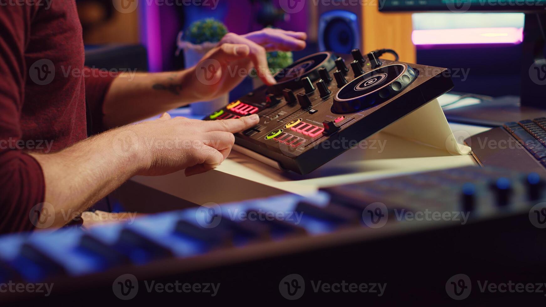 Experienced audio engineer uses mixing board to create new song in recording home studio. Post production equipment and tools on computer, operates digital audio workstation software. Camera A. photo