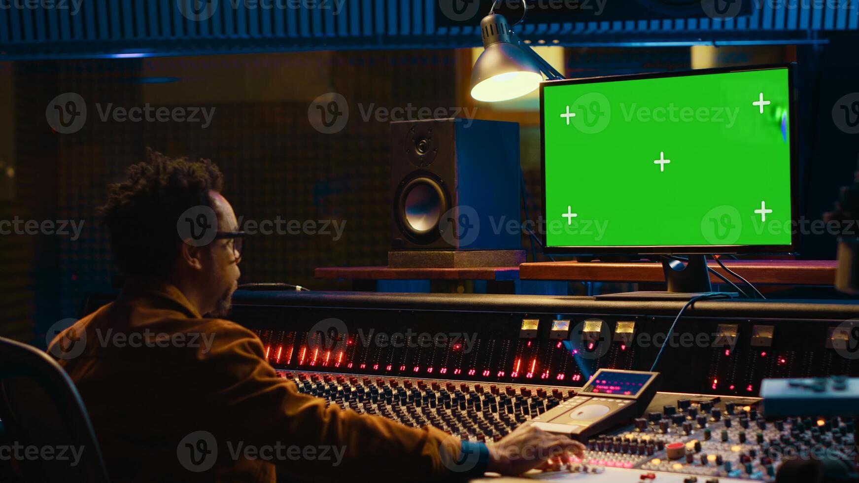 African american sound engineer working in control room with mixing console, tracking music and editing by adjusting volume levels. Skilled technician adjusting volume levels with buttons. Camera A. photo