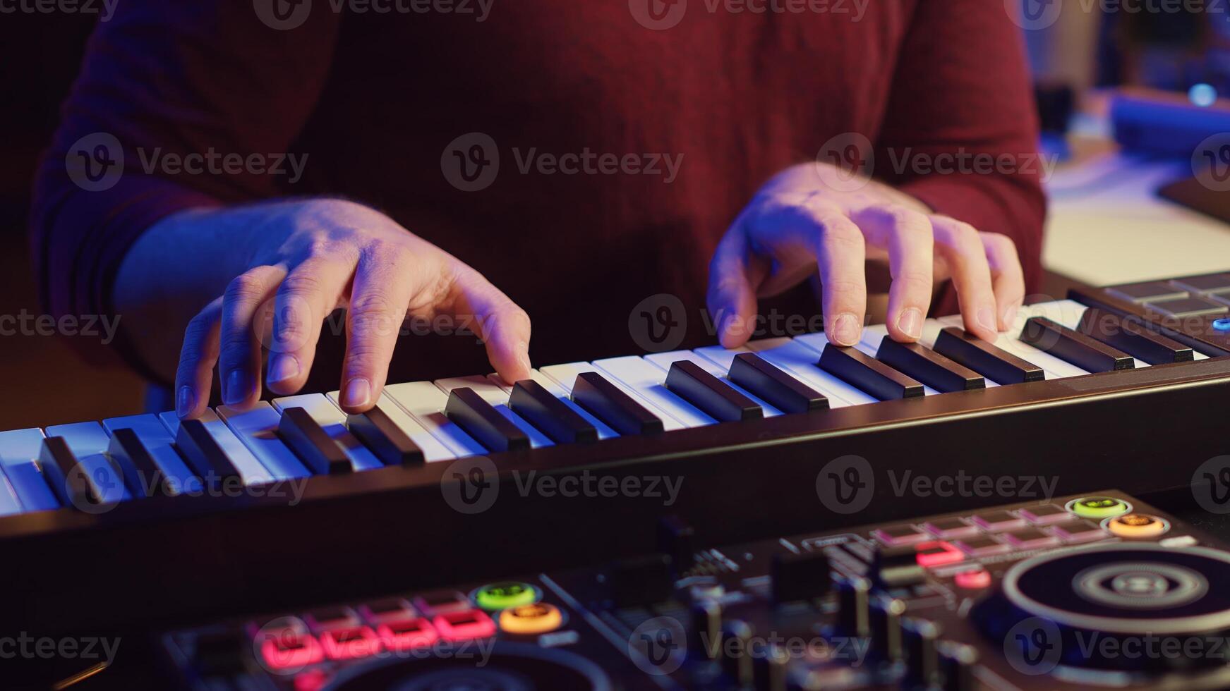 Music producer playing his song on piano keyboard and singing at microphone, recording soundtrack to edit on mixing console. Composer working with synthesizer in home studio. Camera A. photo