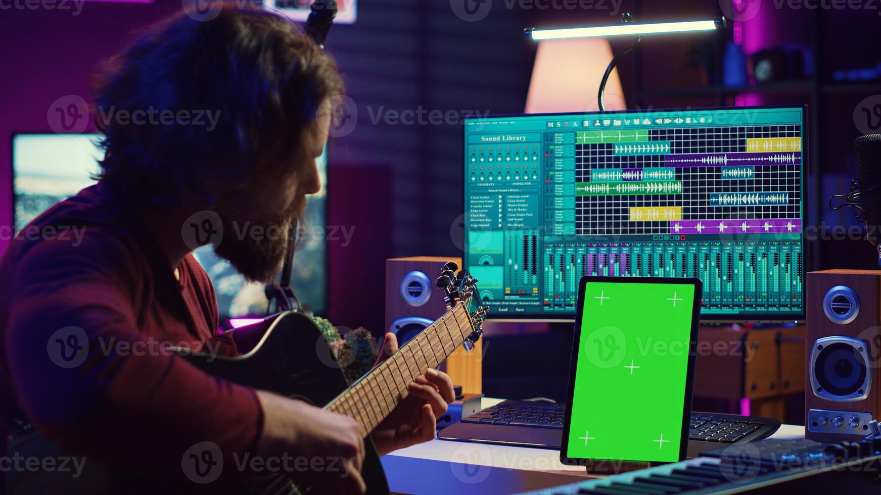 Sound engineer practices playing acoustic guitar using learning app tutorial on phone via greenscreen isolated display. Young musician learning to play instrument with online lessons. Camera A. photo
