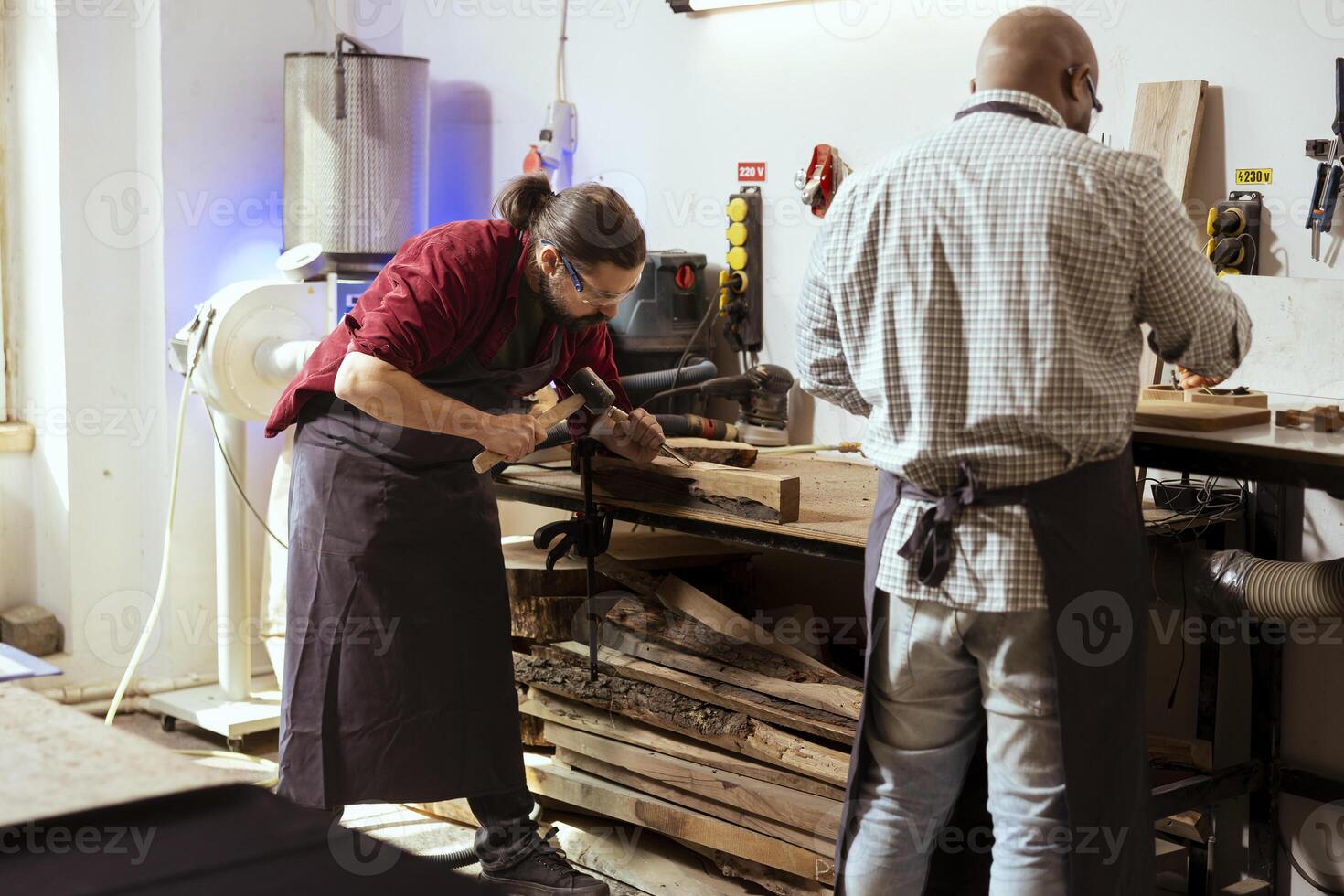 Manufacturer carving designs into wood using chisel and hammer, wearing safety glasses to avoid injury. Artisan shaping wooden pieces using protective equipment to prevent workplace accidents photo