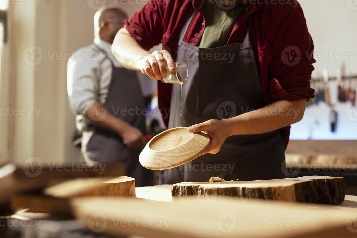 Man pouring lacquer on wood surface in assembly shop, starting restoration project. Woodworking professional in carpentry shop dripping oil on plank, building protective layer on it photo