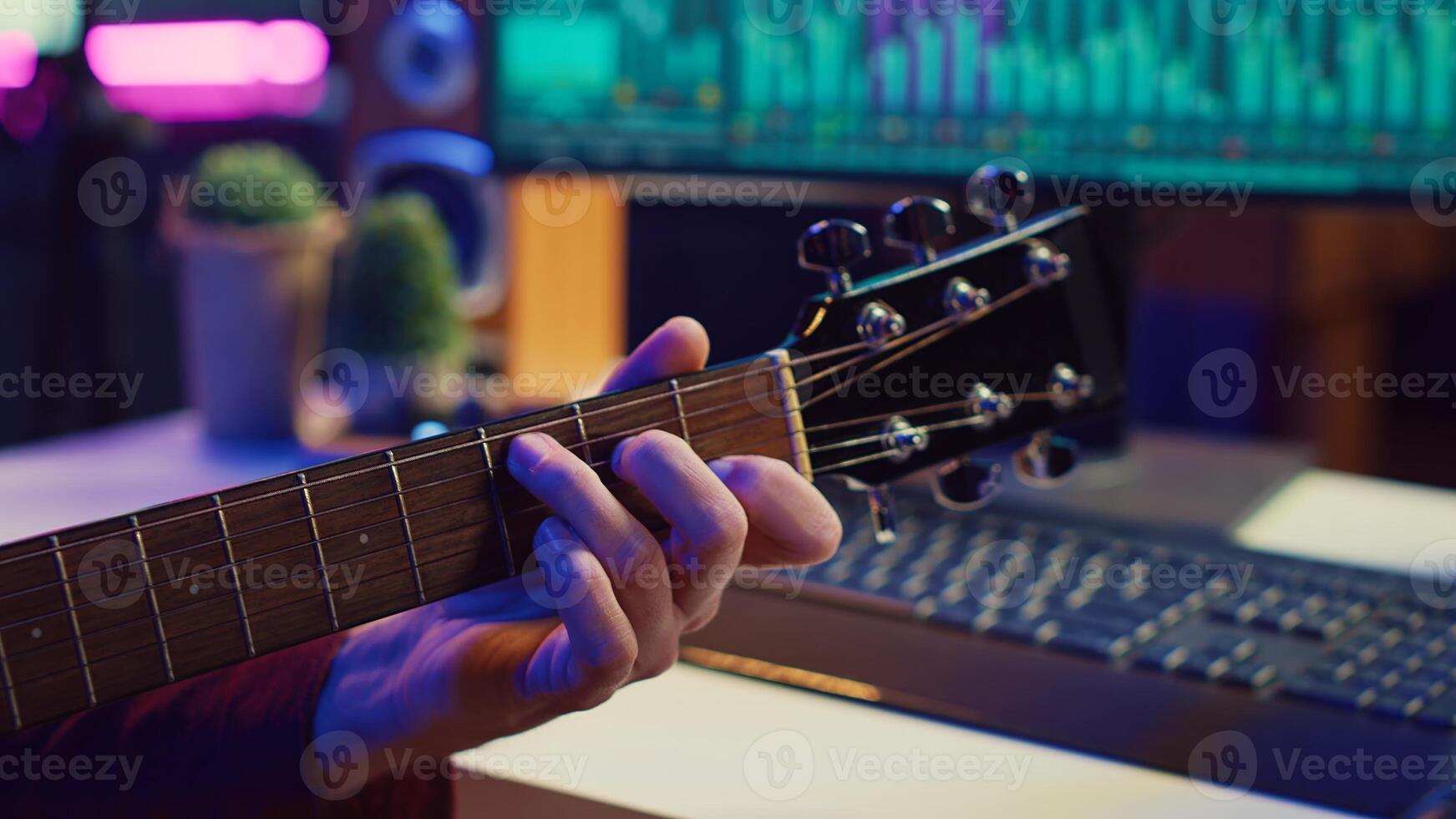 Professional songwriter playing guitar and using soundboard for mixing and mastering tracks. Producer composing a song with audio equipment at home recording studio, equalization tools. Camera A. photo