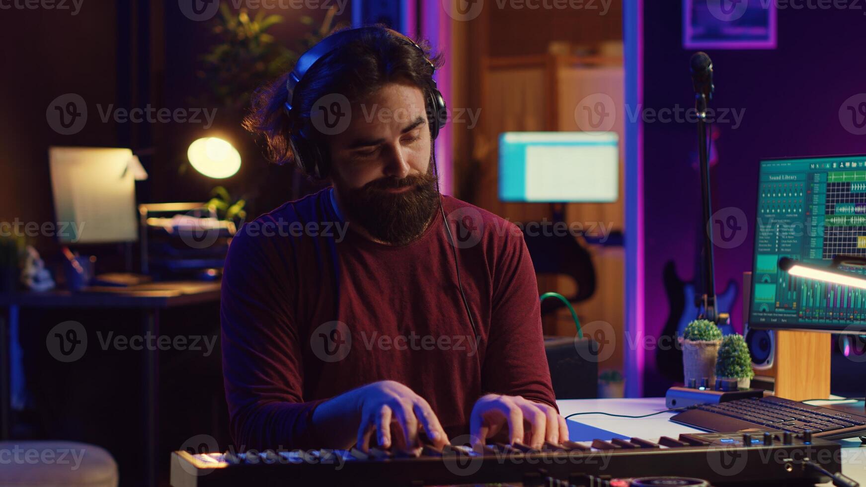 Young artist composing a song on electronic piano keyboard at home recording studio. Audio engineer playing MIDI controller, working on producing a soundtrack, soundboard tools. Camera A. photo