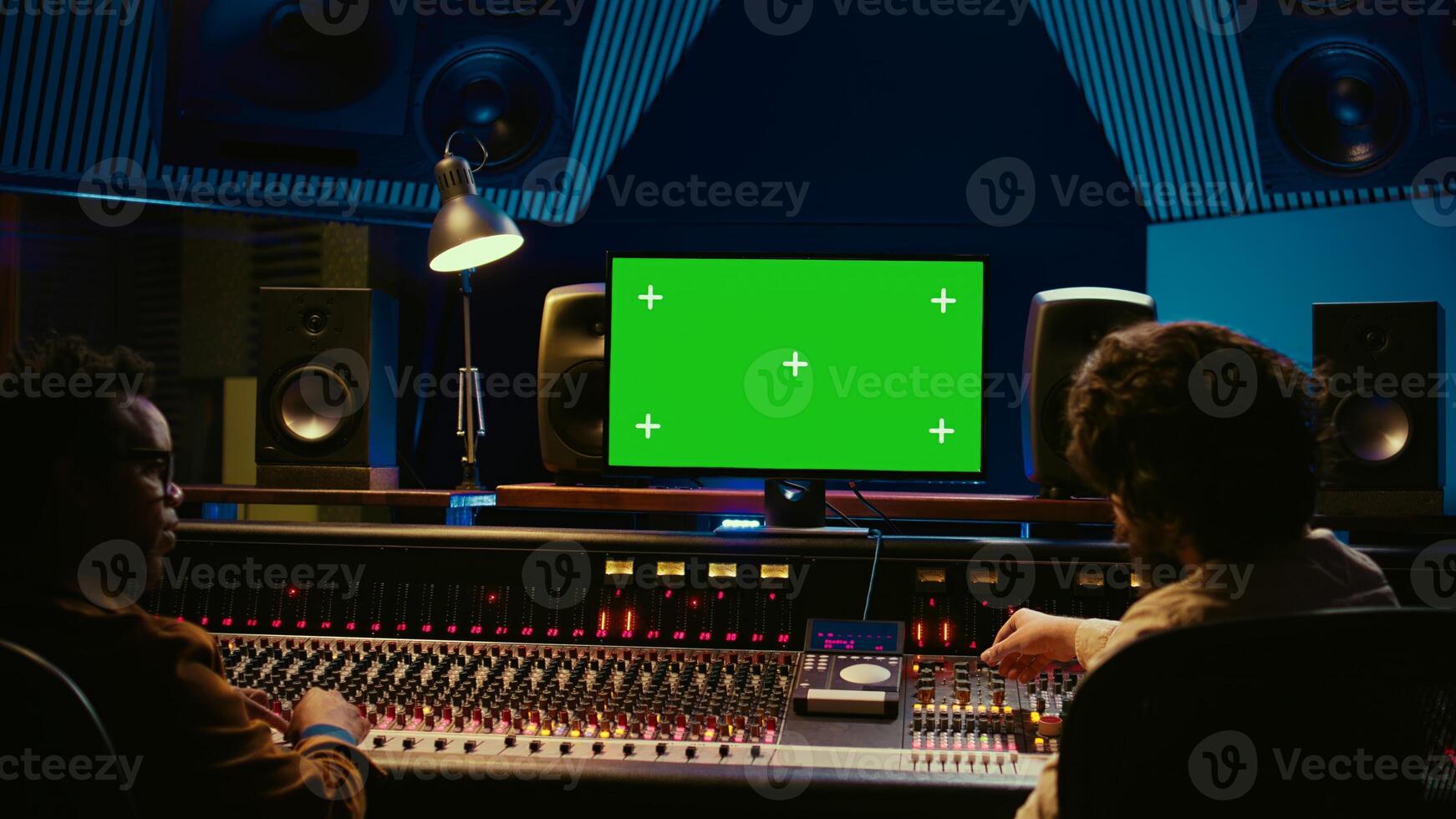 Team of music engineer and artist recording tracks on greenscreen, processing sounds to create a new song. Musician working closely with producer to make high quality tunes. Camera A. photo