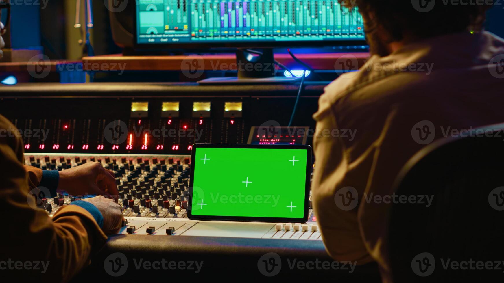 Artist and sound designer examine digital editing software and mockup on tablet, collaborating on composing a hit for new album. Musician working with audio technician in studio. Camera A. photo
