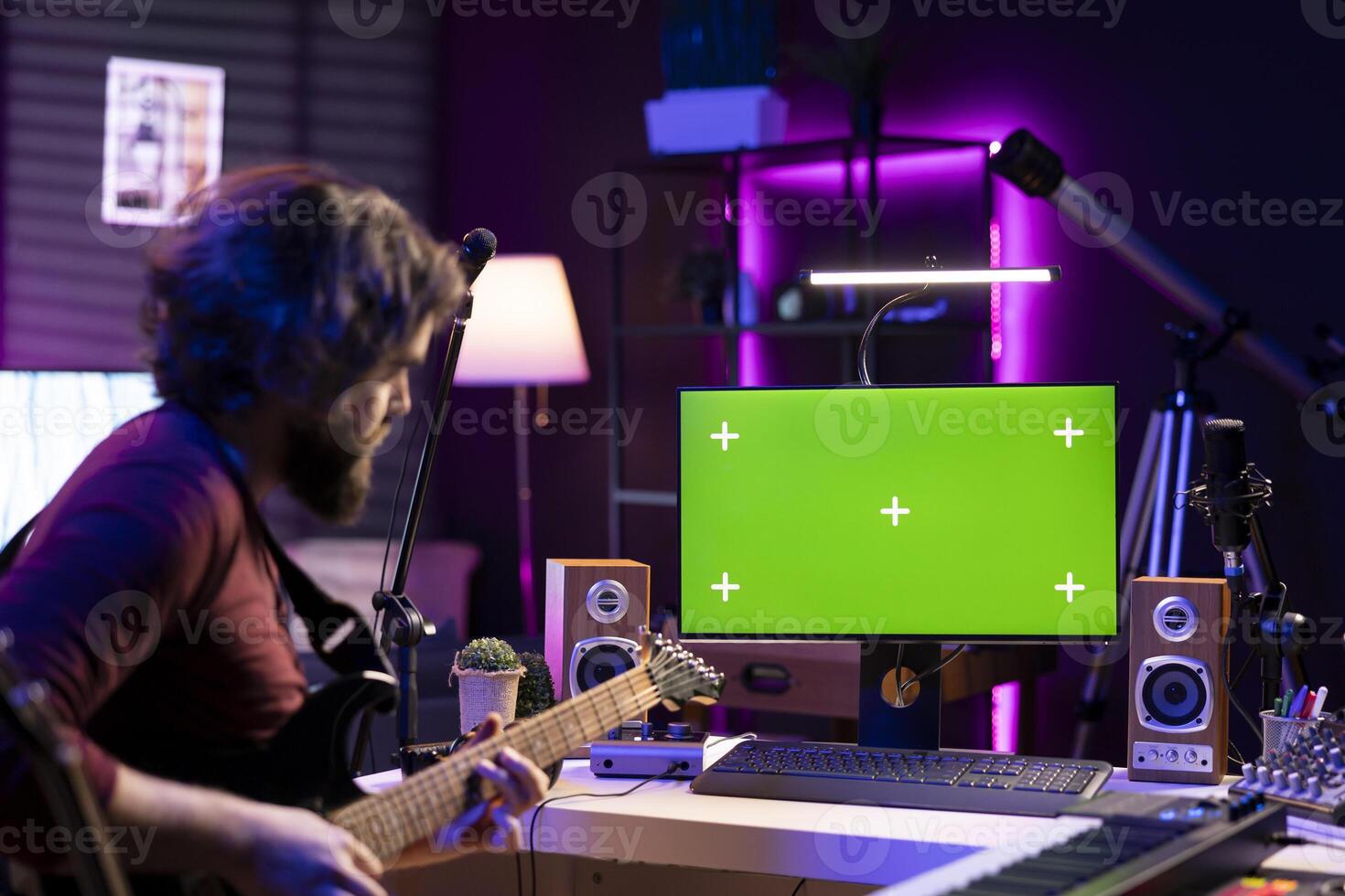 Young musician learning to play acoustic guitar with online lessons via computer with greenscreen layout in home studio. Audio engineer playing instrument to learn new accords, music industry. photo