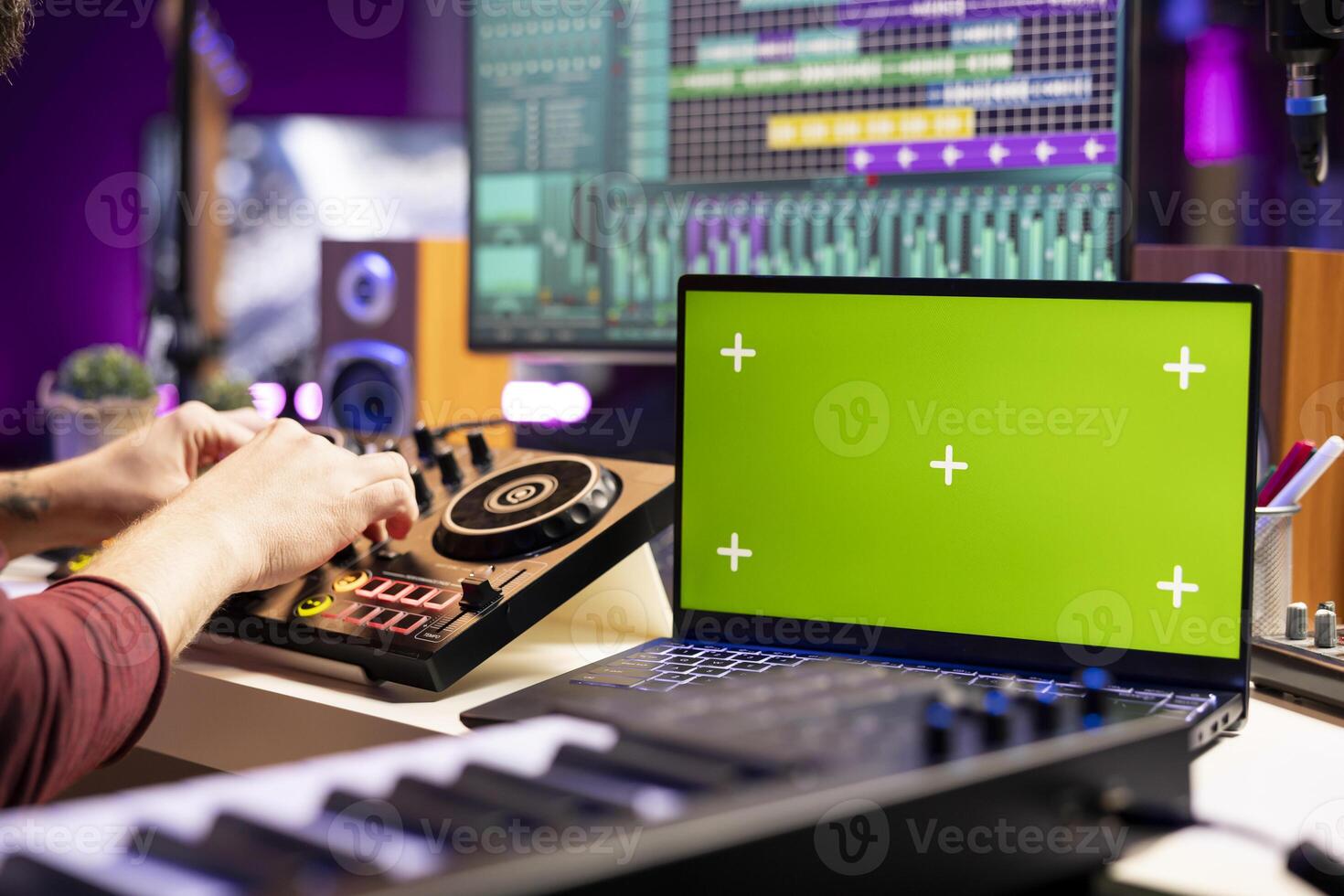 Sound engineer twisting pre amp knobs on mixing console in home studio, using laptop with greenscreen template. Music producer editing soundtracks, stereo equipment on daw software. photo