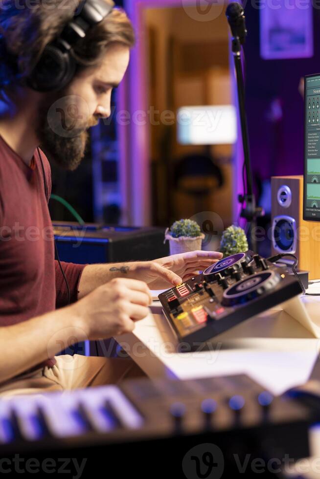 Music engineer editing his soundtracks on mixing console, using control panel board an pre amp knobs. Young artist creating new tunes on post production with stereo equipment, home studio. photo
