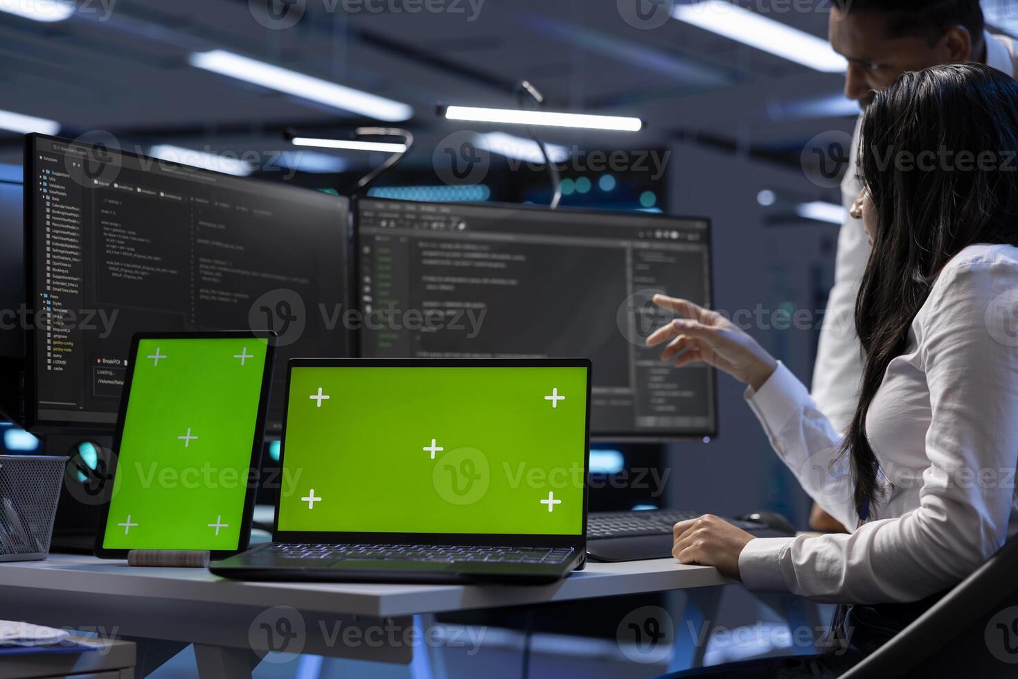 Engineers in data center using mockup tablet and laptop to check for server issues arising due to high CPU usage. Server hub workers fixing insufficient memory errors with green screen devices photo