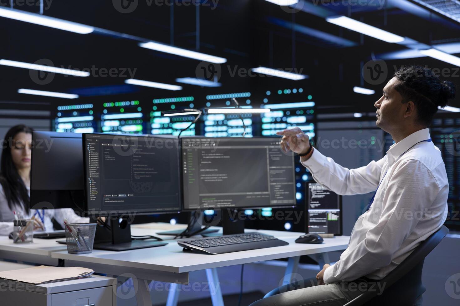 System administrator looking at holograms in data center, monitoring equipment. IT staff member in server farm interacting with futuristic augmented reality AI visualization photo
