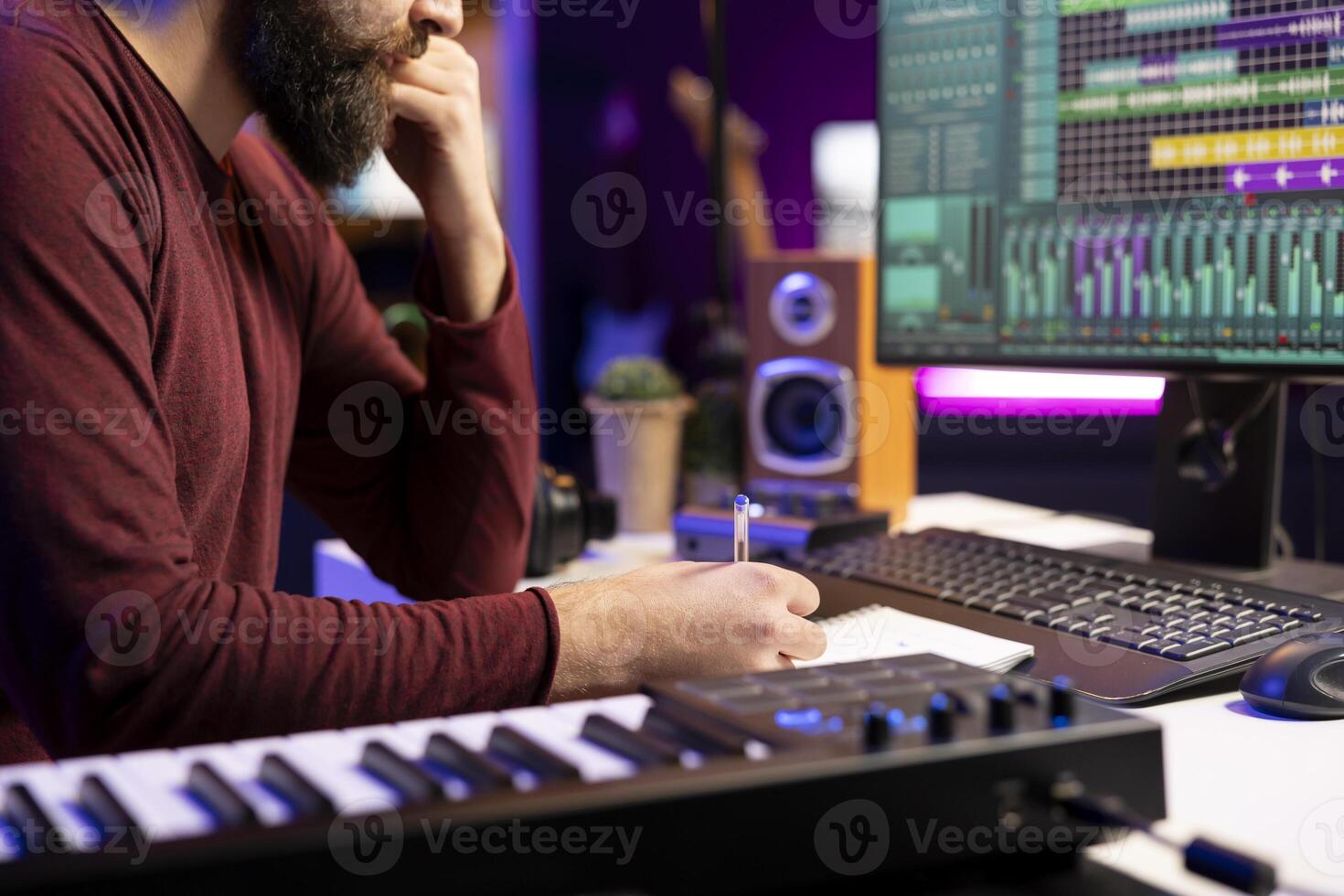 Musician composing new song in his home studio and taking notes, writing down lyrics before recording the tunes. Songwriter producing music with daw software tools and creativity. photo