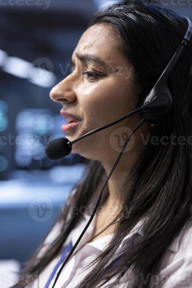 Data center agent in remote call, providing customer support, troubleshooting system bugs. IT expert in server hub carrying out operational interventions requested by clients, talking in microphone photo