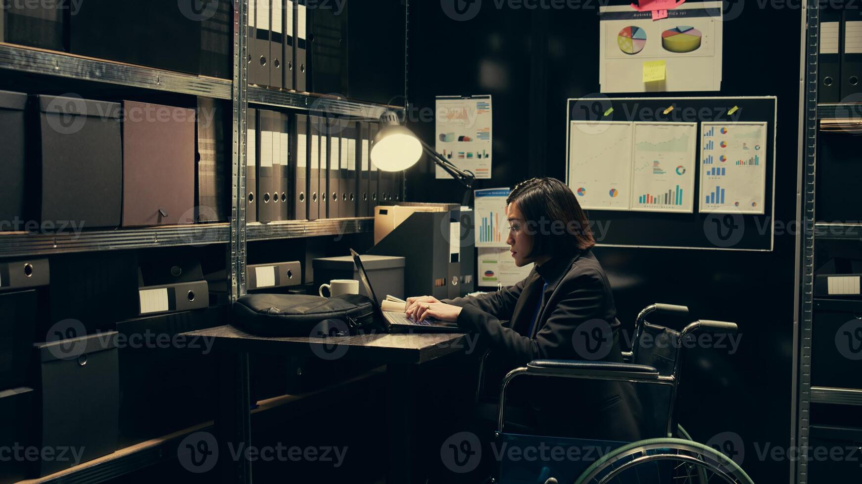 Wheelchair user and inspector analyzing criminal records in police archive room, cross reference data from cases to identify similarities. Team of agents compile notes on crime trends. Camera B. photo