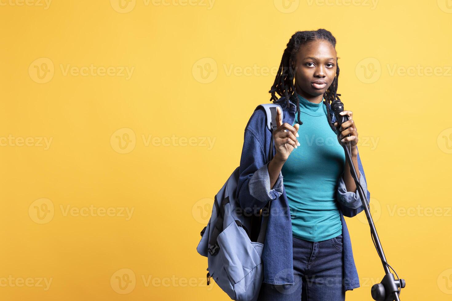 Portrait of african american motivational speaker talking in microphone, addressing audience, isolated over studio background. Expressive BIPOC lecturer using mic, inspiring motivation photo