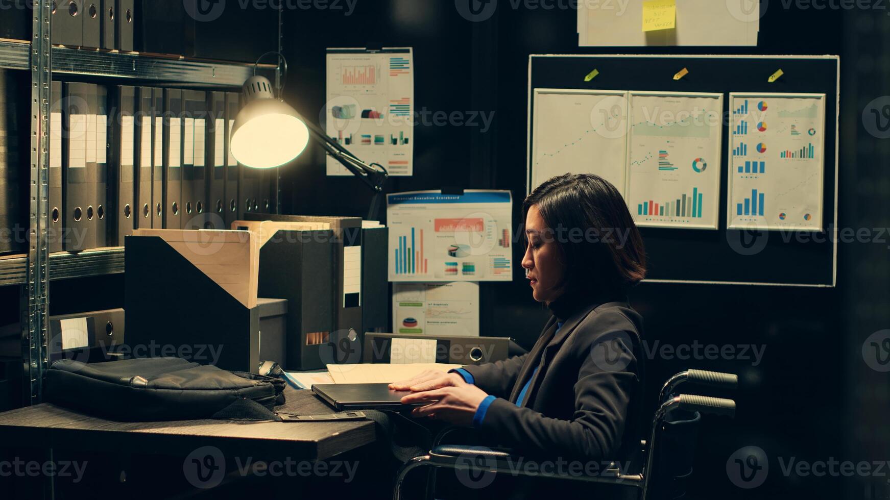 Detective with impairment studying classified folders in archive room, gathering information from surveillance files and witness statements. Agent working in a disability friendly space. Camera A. photo
