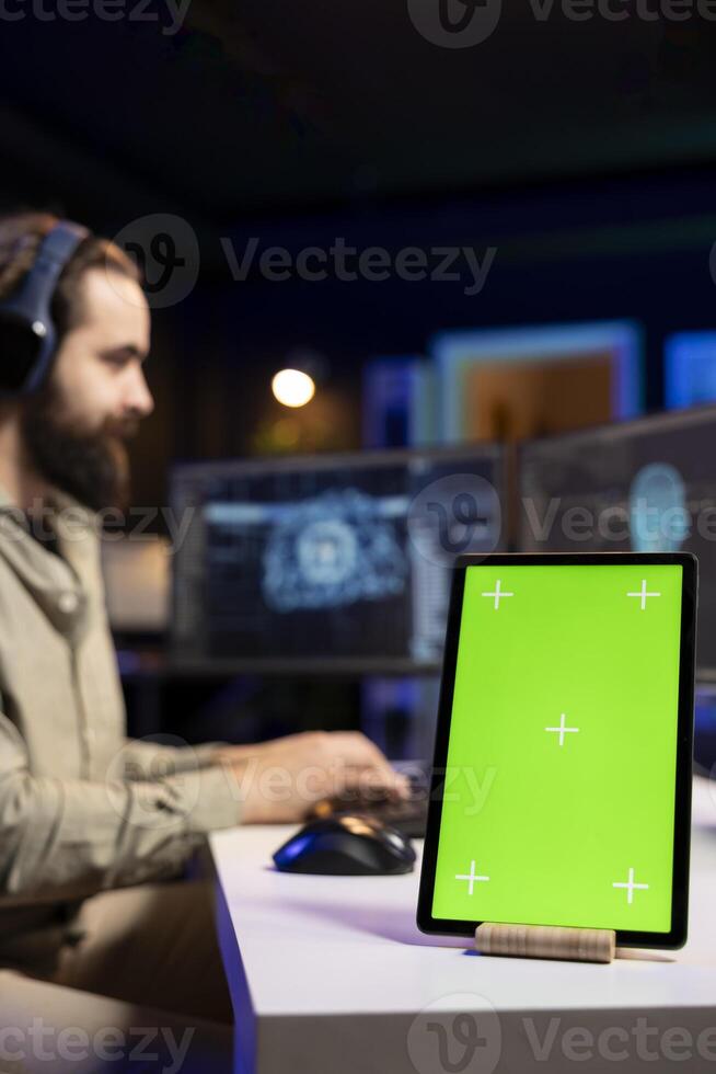 Focus on chroma key tablet with sentient AI in blurry background gaining humanoid form. Isolated screen device next to self aware artificial intelligence on PC discussing with engineer, close up photo