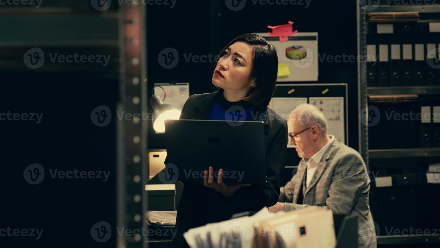 Private investigator organizes archived files for easy access, searching for old file cases to cross reference data. Law enforcement agent looking for classified folders in archive room. Camera B. photo