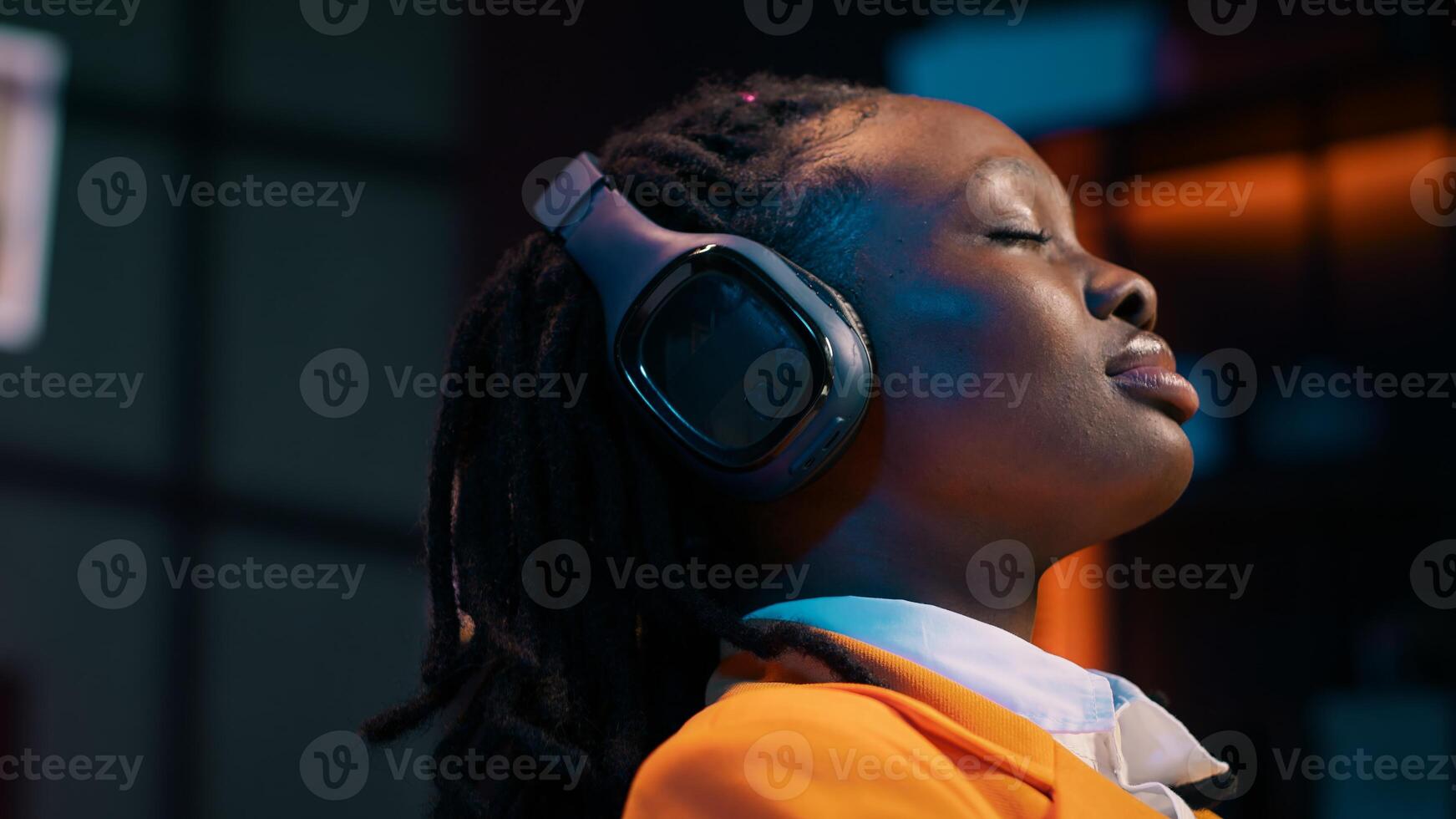 Carefree student finishes creating a presentation and relaxes with music on audio headset, resting after long researching session. African american girl chilling with ambience tunes. Camera A. photo