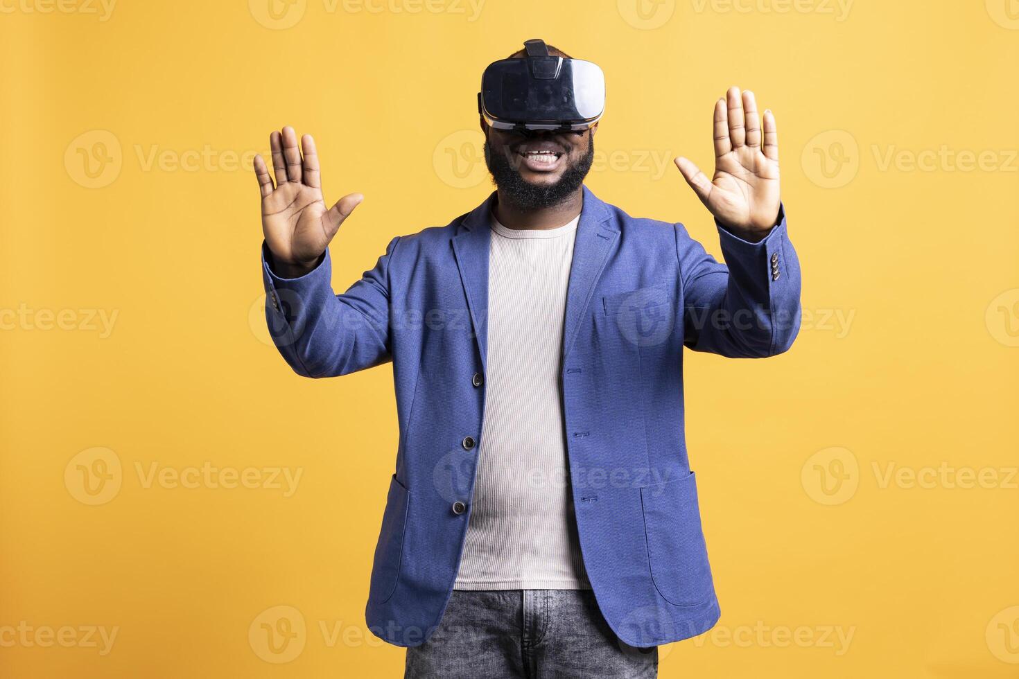 Excited tech fan wearing virtual reality goggles, doing hand gestures. African american cheerful man using high tech futuristic modern VR glasses, making tactile touching gesturing, studio background photo