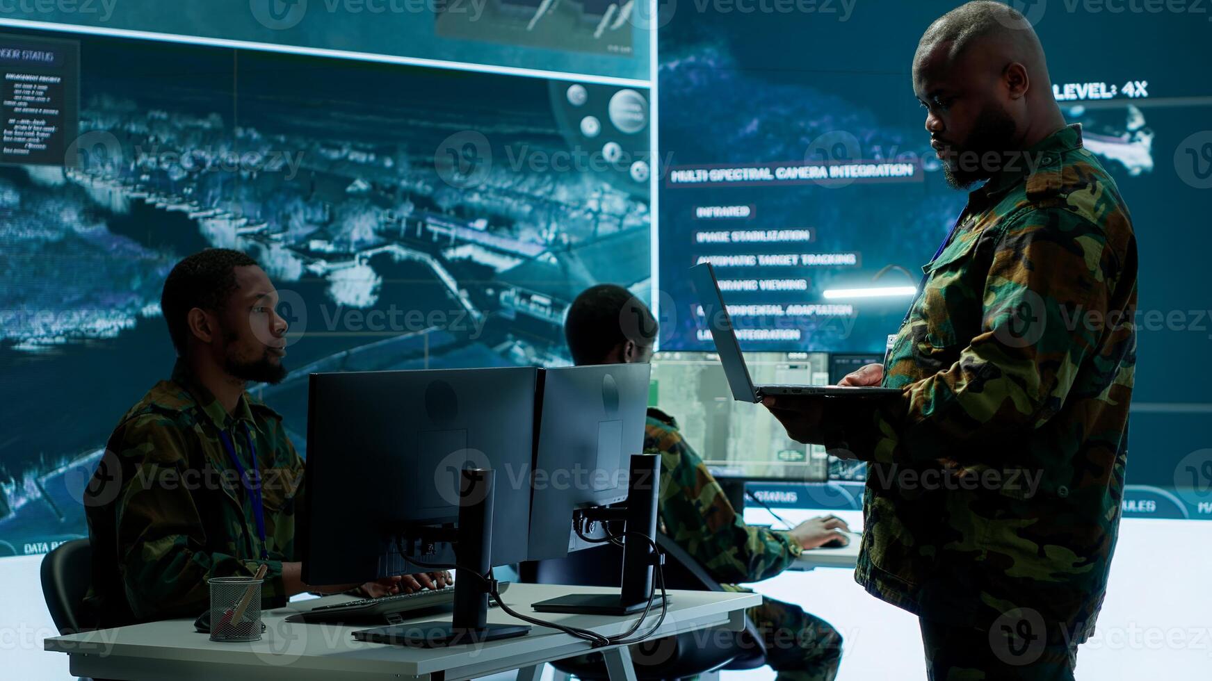 Cybersecurity team operates in an advanced military command center, surveillance systems and data protection. Army personnel work on national security operations using high tech gear. Camera A. photo