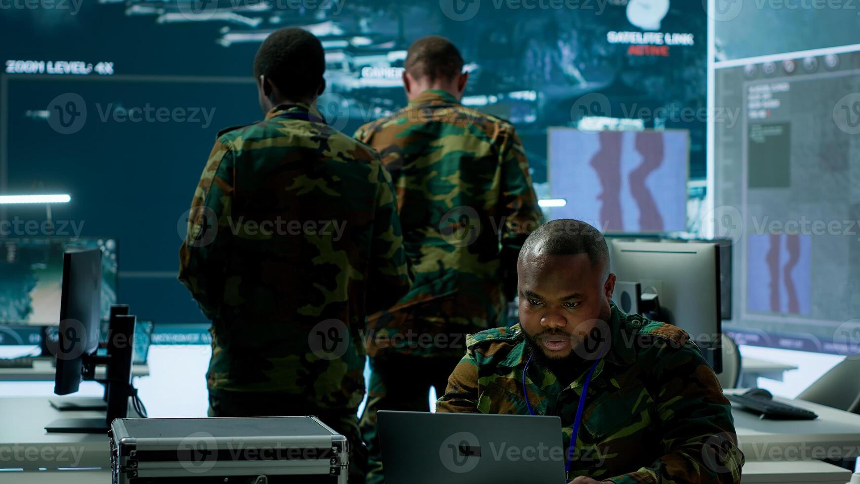 In a high tech military office, soldiers team analyze real time data collected by surveillance system. Staff interpret intelligence and coordinate operations to ensure national defense. Camera A. photo