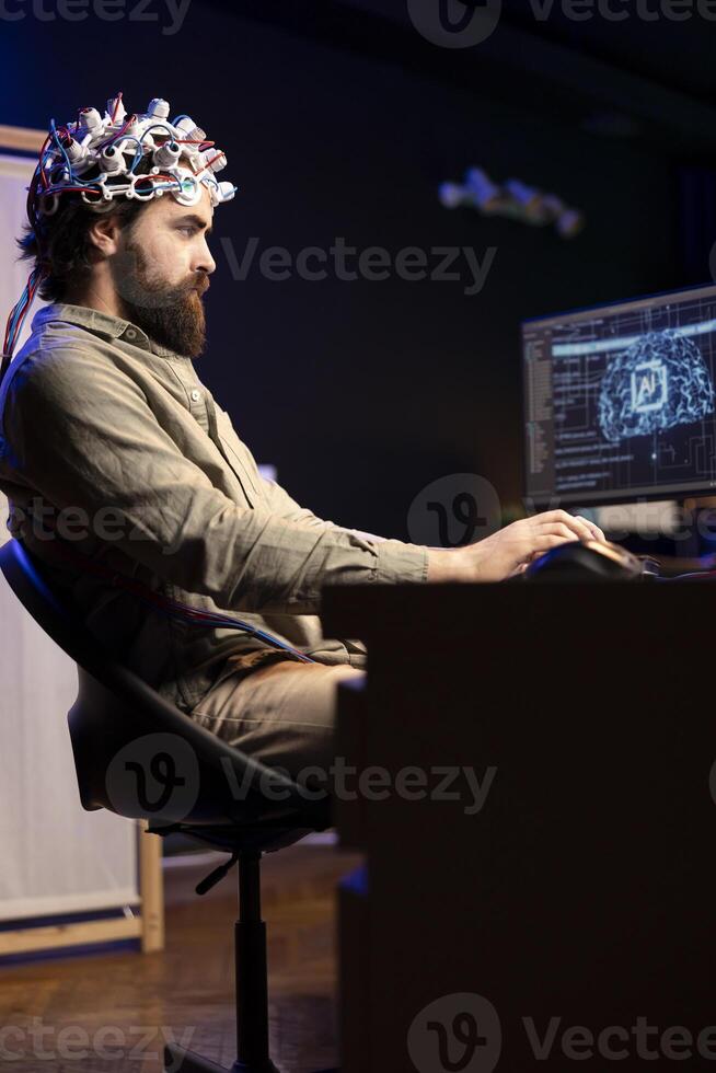 Programmer using EEG headset translating thoughts into PC commands using brainwave signals. Man controlling computer functions using his mind, helped by biosensor technology research photo