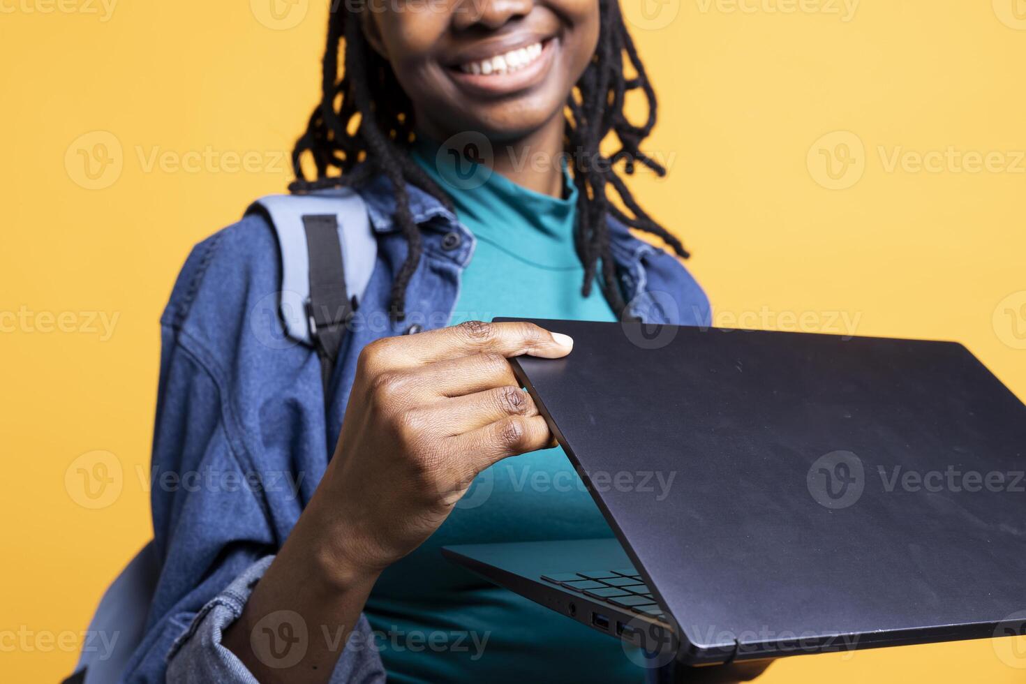 Merry woman opening laptop to prepare for school exam, isolated over studio background, close up shot. Upbeat african american student using notebook to do research project photo