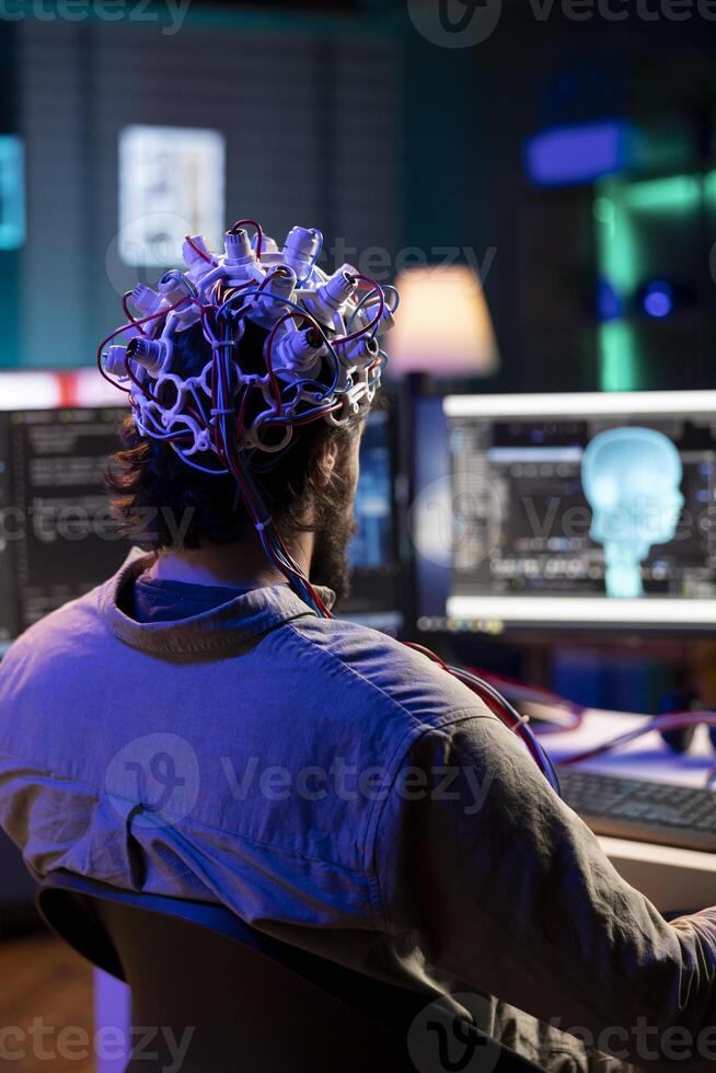 Software engineer using EEG headset translating thoughts into PC commands using brainwave signals. IT admin controlling computer functions using mind, helped by biosensor technology research photo