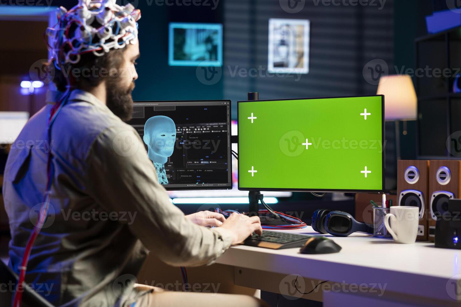 IT technician using EEG headset device translating thoughts into commands on green screen PC display on desk. System administrator controlling chroma key computer functions using mind photo