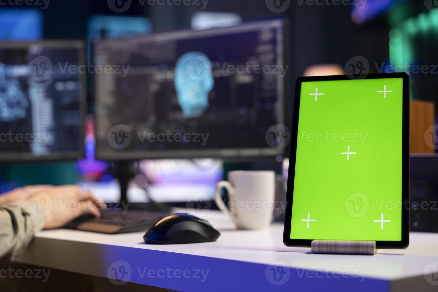 Focus on isolated screen tablet next to man in blurry background talking with AI gaining consciousness. Chroma key device on desk next to programmer, chatting with artificial intelligence, close up photo