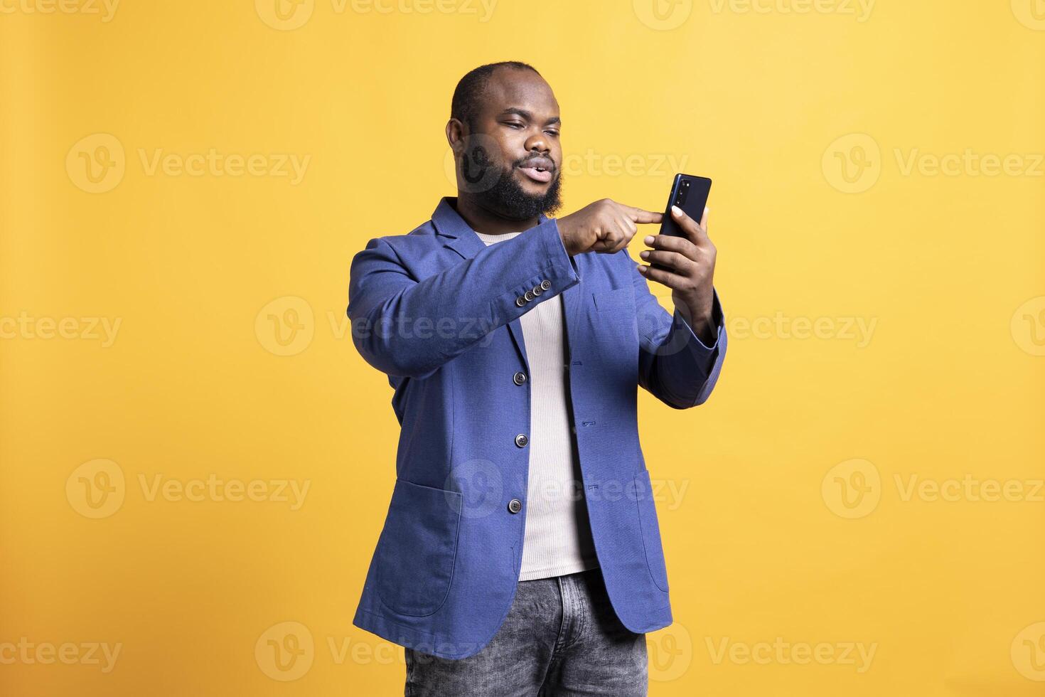 BIPOC man texting best friend using smartphone, reading messages. Relaxed african american person having fun while chatting with mate on mobile phone, isolated over studio background photo