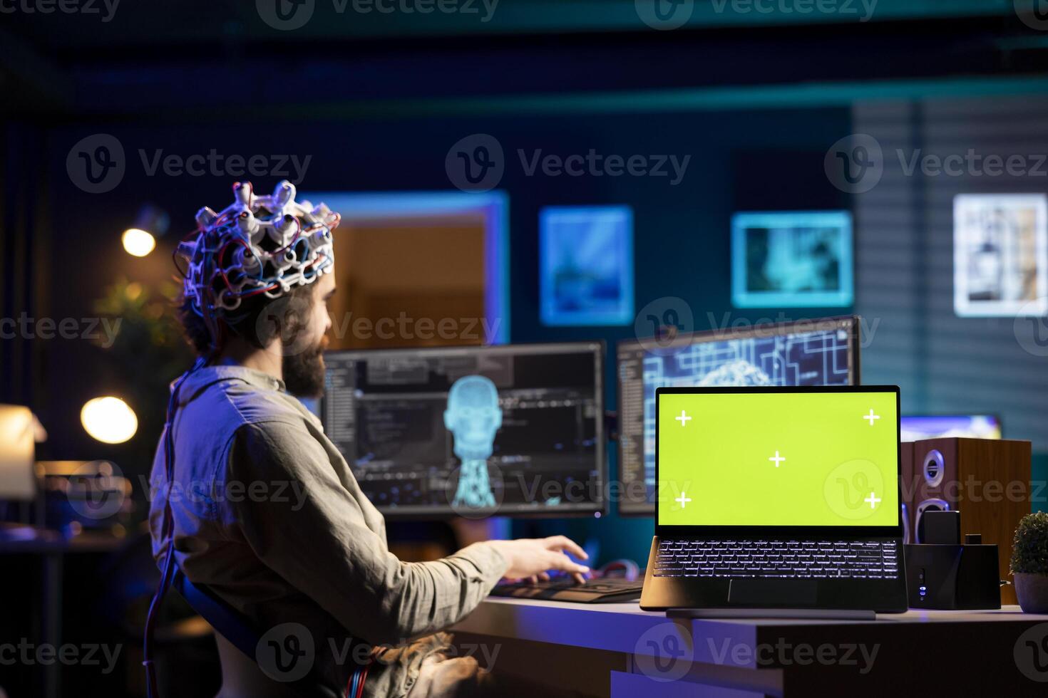 Software engineer with EEG headset starting mind upload trying to gain bionic powers, isolated screen on laptop. IT admin using high tech neuroscientific gear and chroma key notebook photo