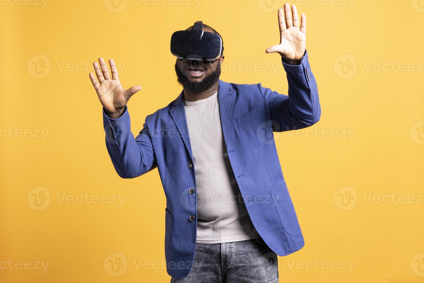Tech enthusiast wearing virtual reality goggles, doing swiping gestures. BIPOC man using high tech futuristic modern VR glasses, making tactile touching gesturing, studio background photo