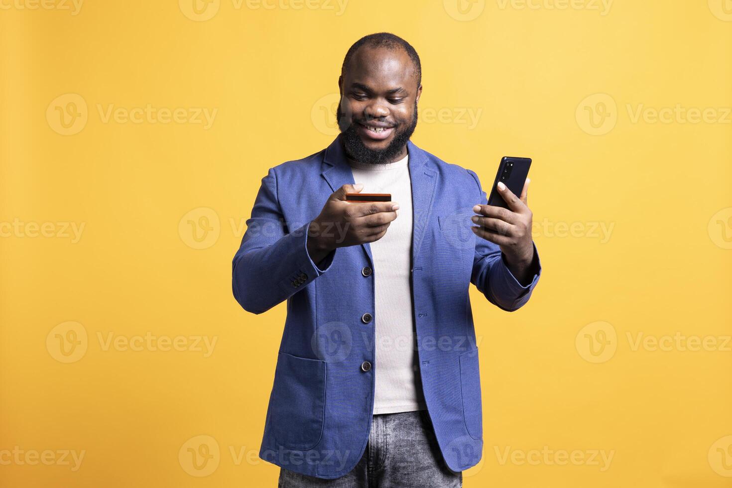 Upbeat man adding payment method on phone, enjoying himself, isolated over studio background. Joyous person delighted to do internet shopping, carefully typing credit card information photo