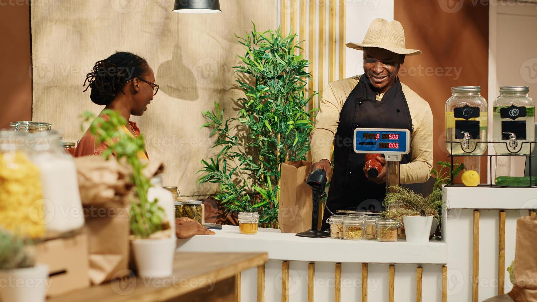 African american seller preparing bag with products for client, weighting fruits and veggies. Merchant scanning bulk items in recyclable jars, woman supporting nonpolluting business. Camera 1. photo