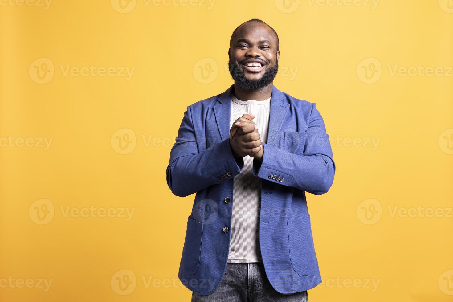 Portrait of happy african american man posing with hands put together, looking pleased, isolated over studio background. Lively radiant BIPOC person smiling, feeling satisfied photo