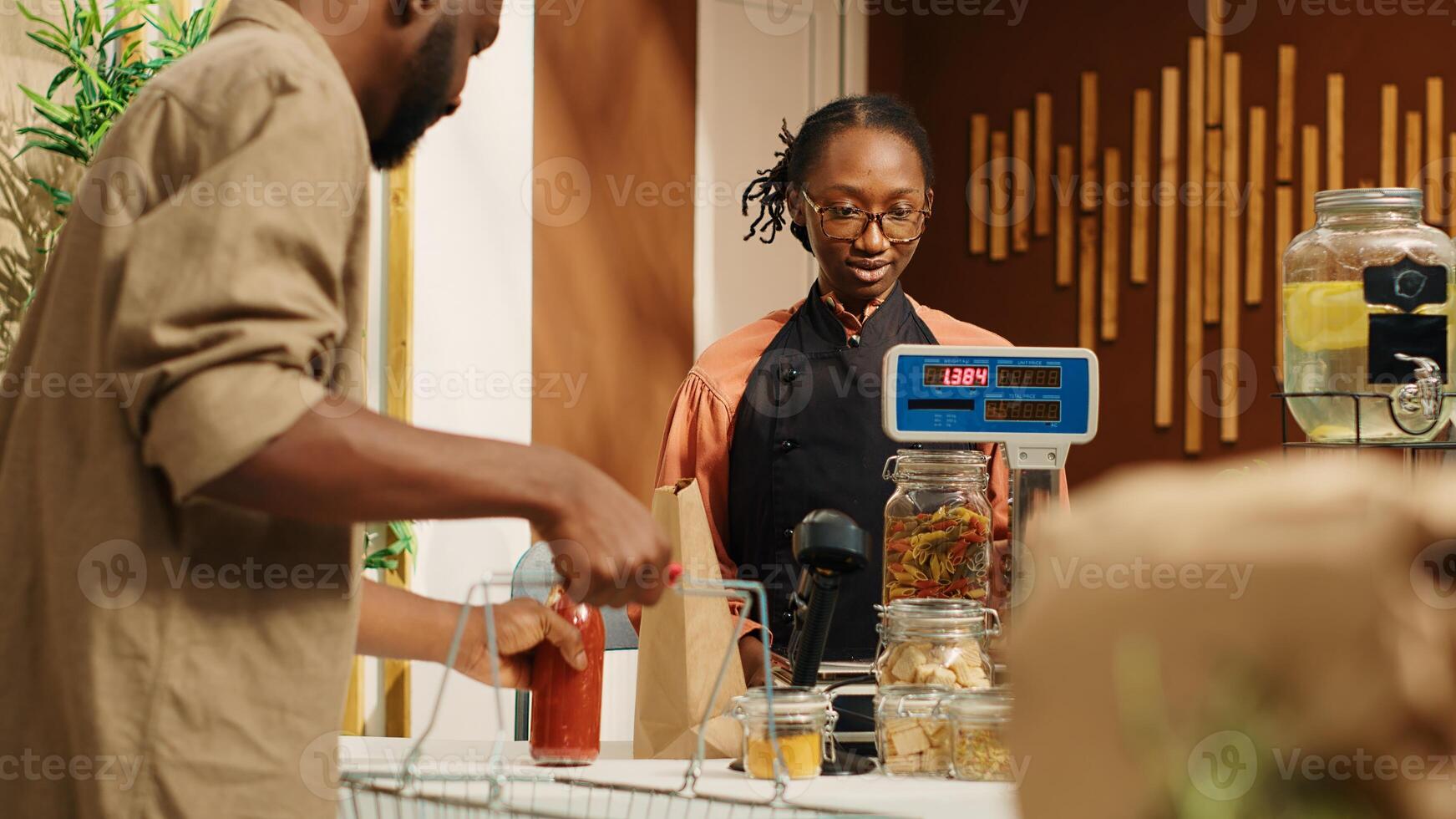 Merchant weighting organic produce for customer at checkout, placing all fresh fruits and veggies on scale at cash register. Woman vendor selling eco friendly nonpolluting merchandise. Camera 1. photo