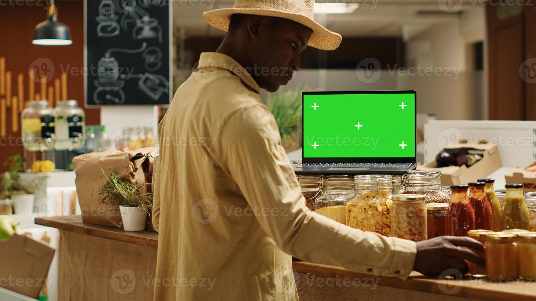 Client looking at organic products in recyclable jars next to greenscreen, shopping for homemade food sauces. African american buyer visiting zero waste eco store, isolated mockup screen. Camera 1. photo