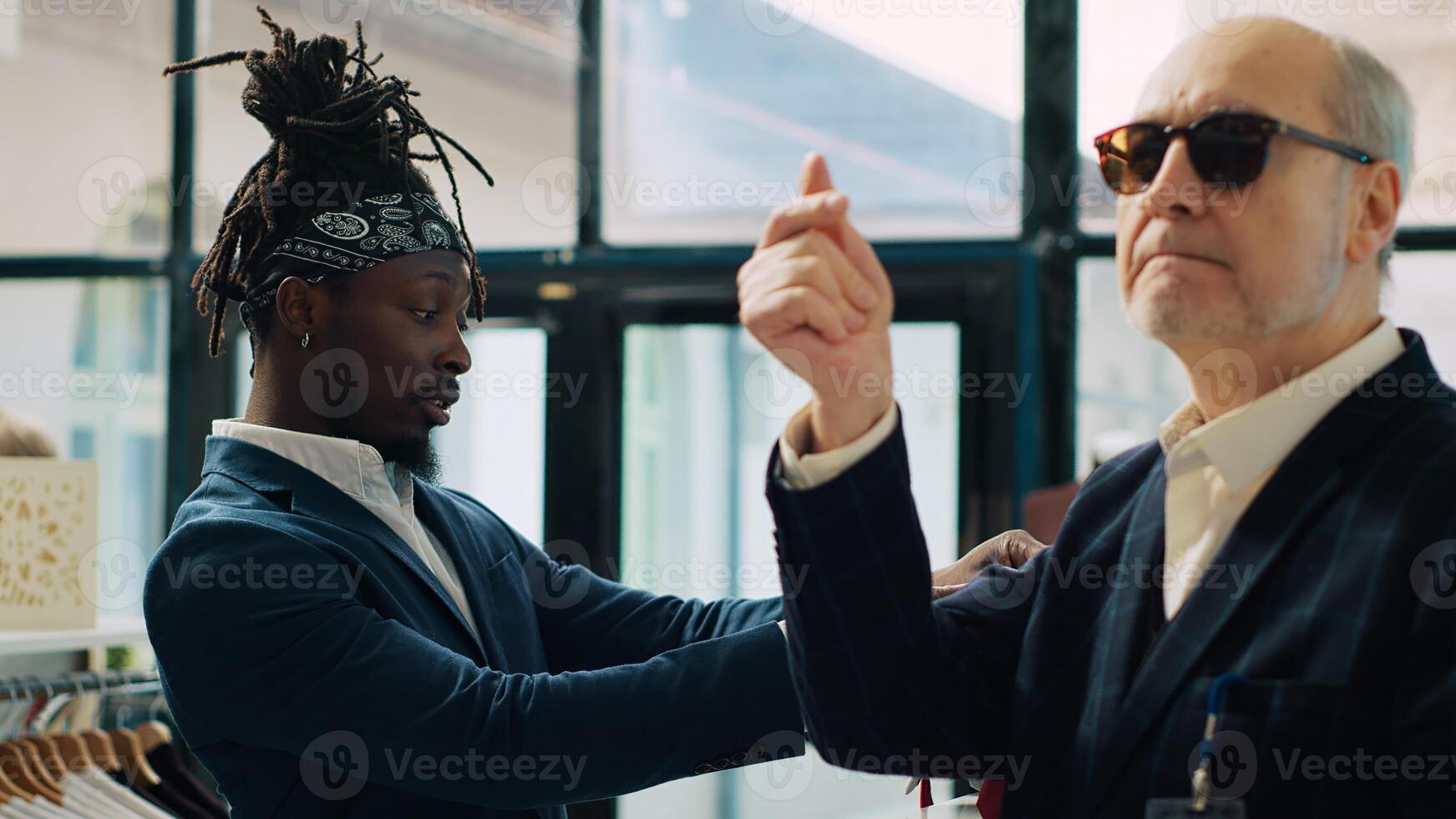 Famous couturier giving order to store assistant to help with finding a tie for his african american client, experienced senior tailor in. Fashion designer shopping for luxury accessories. Camera A. photo