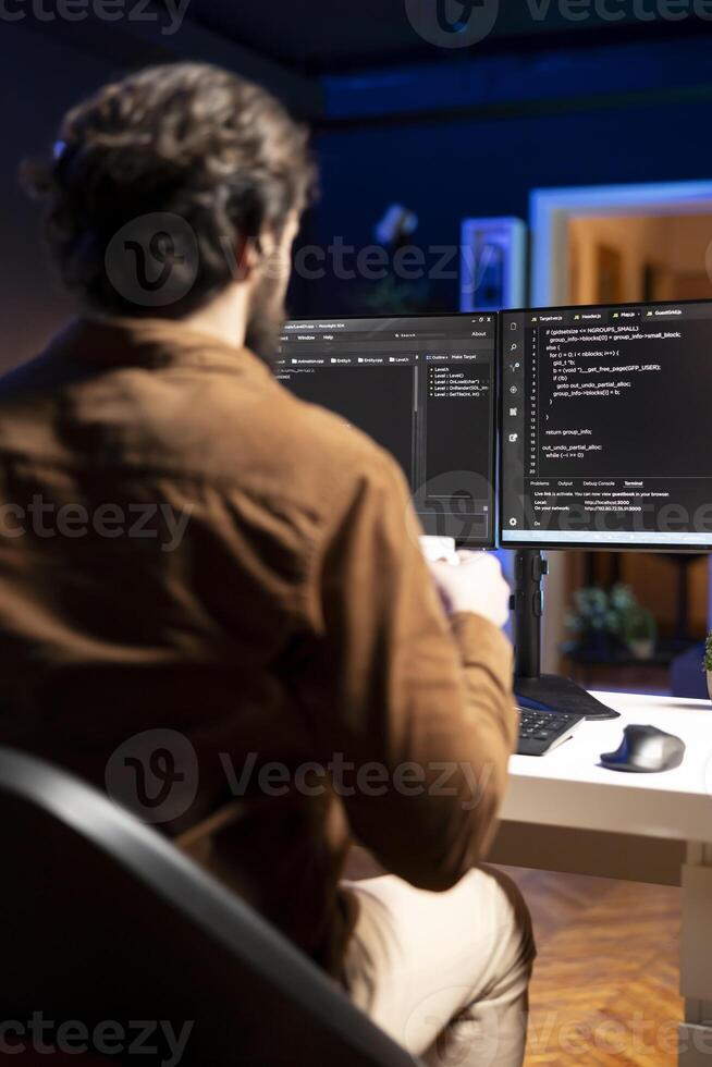 Computer engineer doing software quality assurance, reading source code on screen before implementing it. IT admin inspecting coding on desktop PC, looking to fix potential issues photo